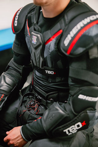 Person wearing a black protective suit with red accents and 'T60x' branding.